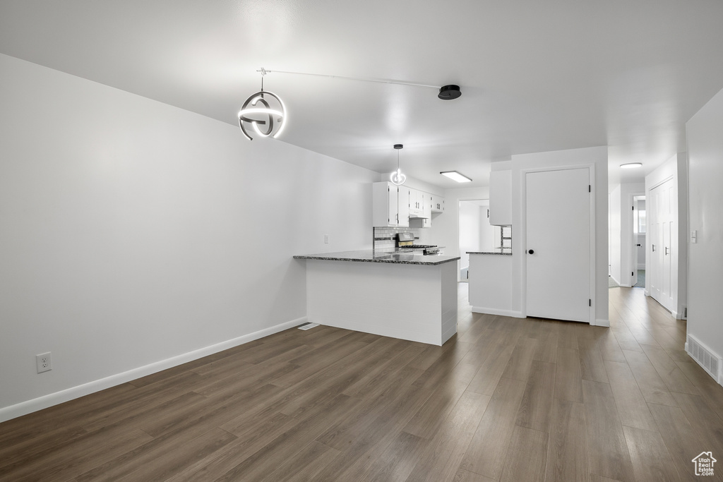 Kitchen with white cabinets, dark hardwood / wood-style floors, pendant lighting, and kitchen peninsula
