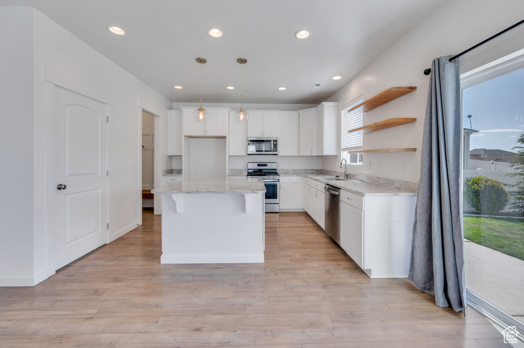 Kitchen featuring a kitchen island, sink, stainless steel appliances, and white cabinetry