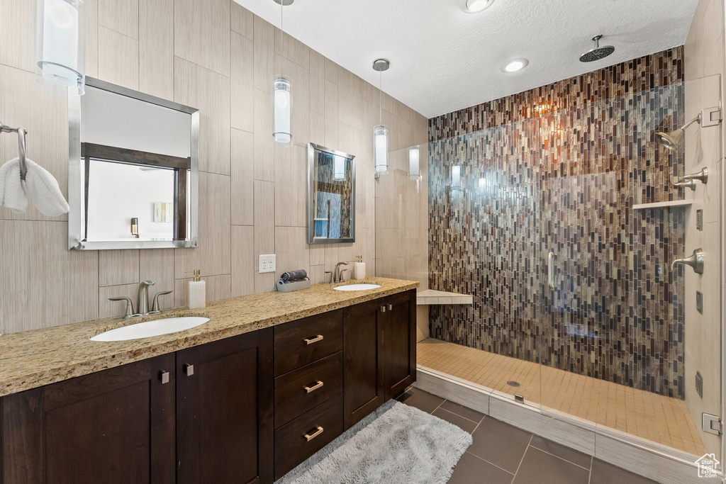 Bathroom featuring tile walls, tile floors, and dual bowl vanity