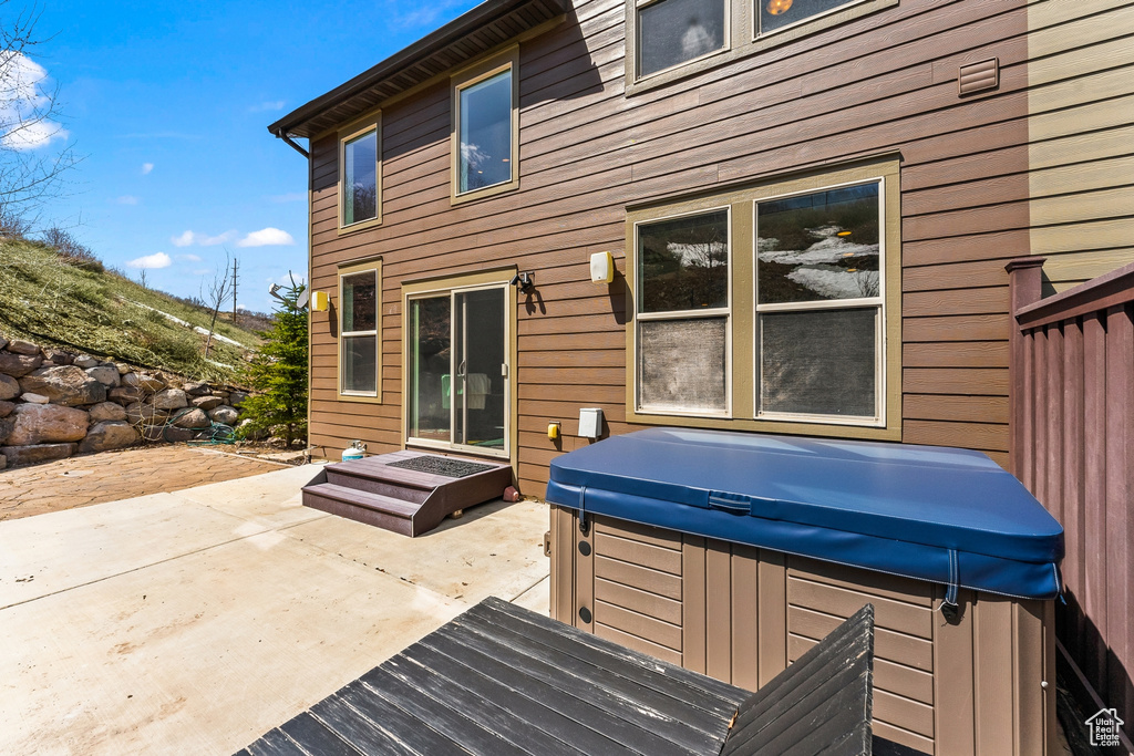 Rear view of property with a hot tub and a patio area