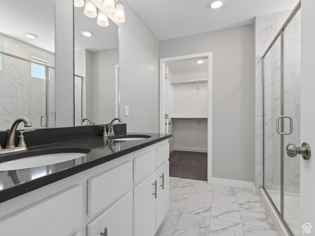 Bathroom featuring dual sinks, tile floors, large vanity, and walk in shower