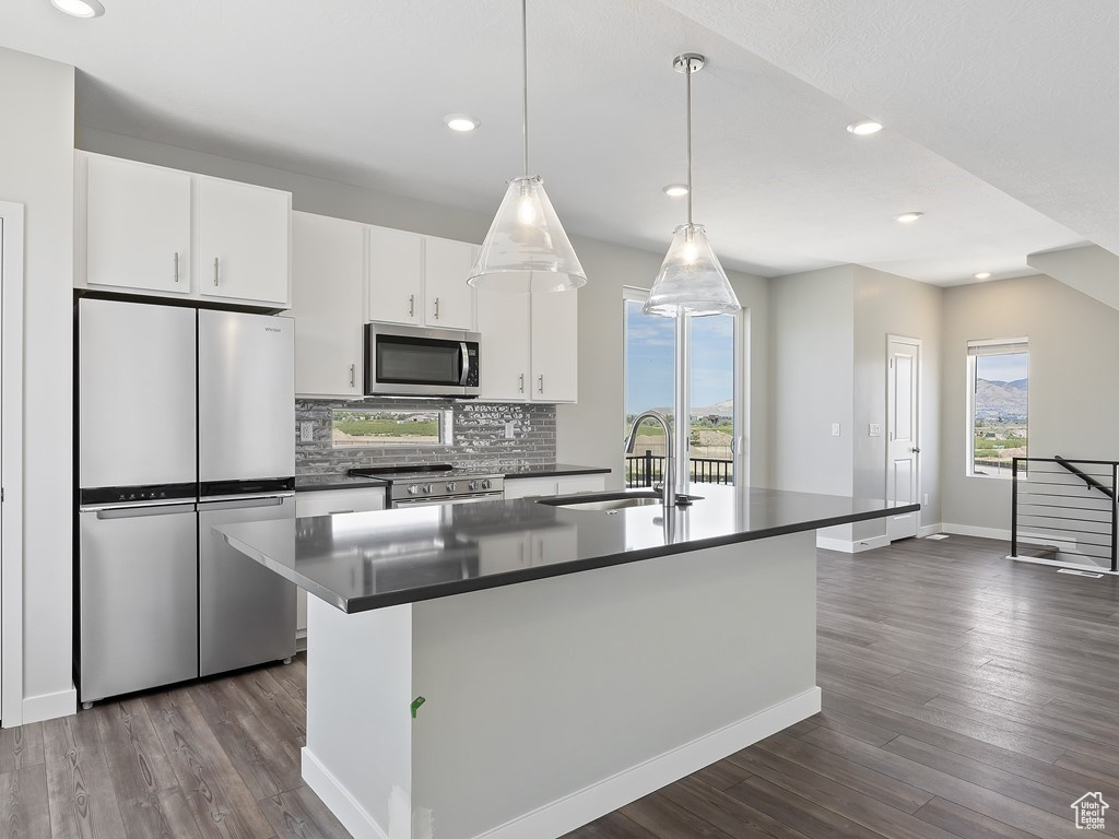 Kitchen featuring appliances with stainless steel finishes, white cabinets, sink, dark hardwood / wood-style flooring, and a kitchen island with sink