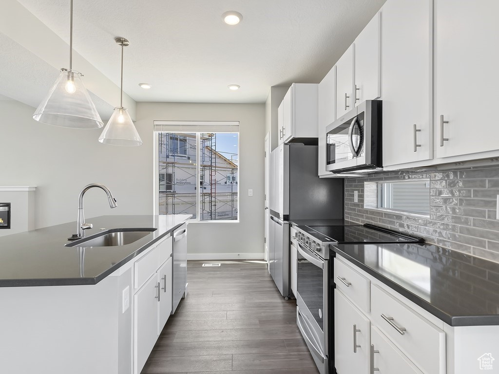 Kitchen featuring appliances with stainless steel finishes, white cabinets, sink, tasteful backsplash, and dark hardwood / wood-style flooring