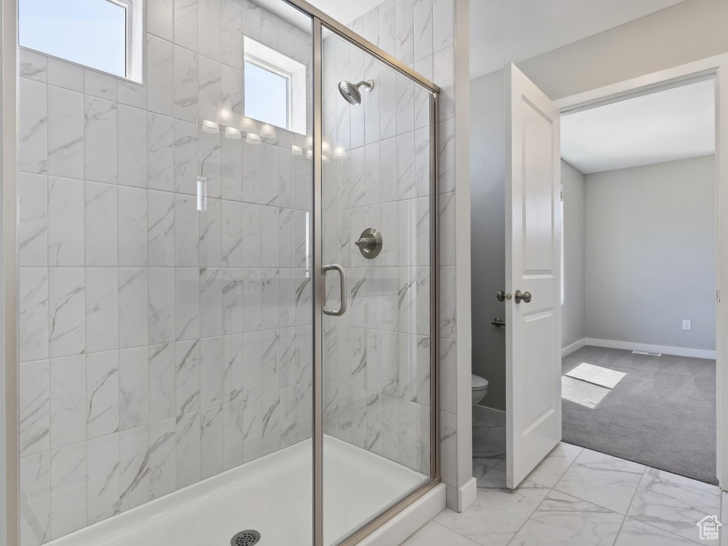 Bathroom featuring walk in shower, plenty of natural light, toilet, and tile flooring