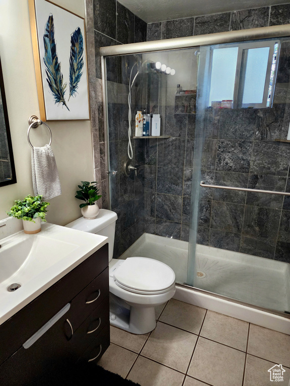 Bathroom with an enclosed shower, toilet, tile floors, and vanity