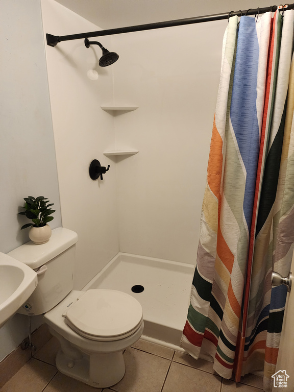 Bathroom with tile floors, toilet, and a shower with curtain
