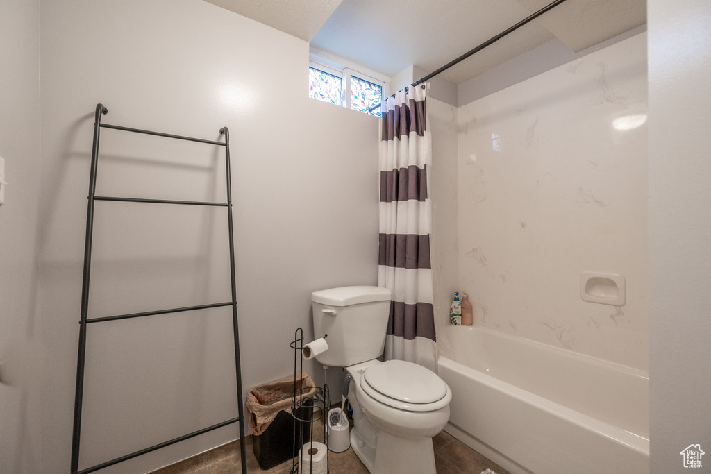 Bathroom with toilet, tile flooring, and shower / bath combo with shower curtain