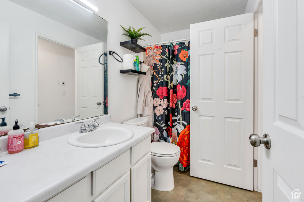 Bathroom with vanity with extensive cabinet space, toilet, and tile flooring