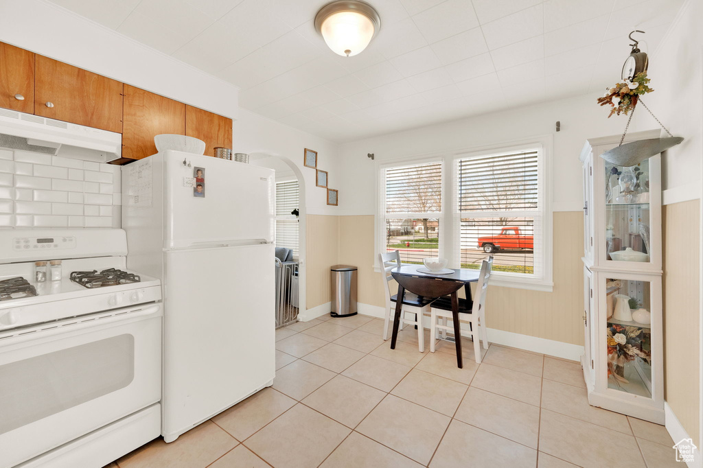 Kitchen with tasteful backsplash, white appliances, and light tile floors