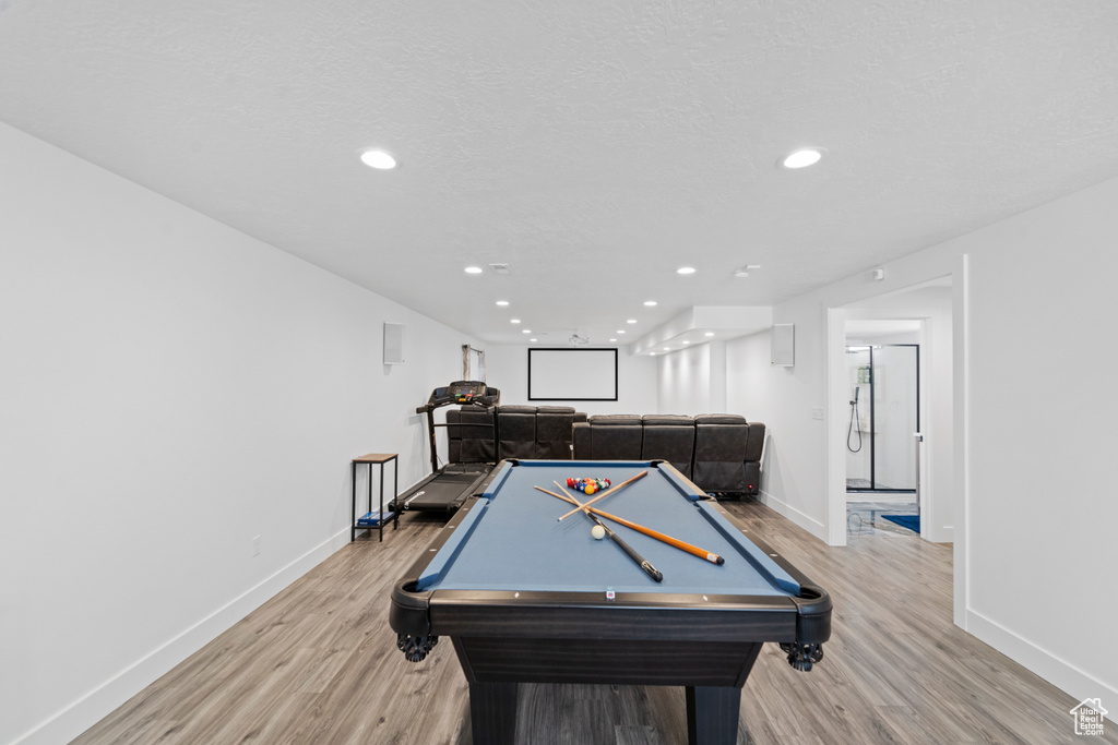 Game room with a textured ceiling, light wood-type flooring, and pool table