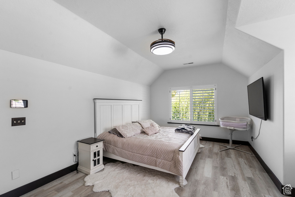 Bedroom with lofted ceiling and light wood-type flooring