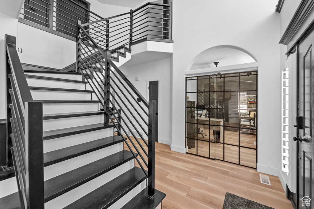 Staircase featuring a high ceiling and light hardwood / wood-style flooring
