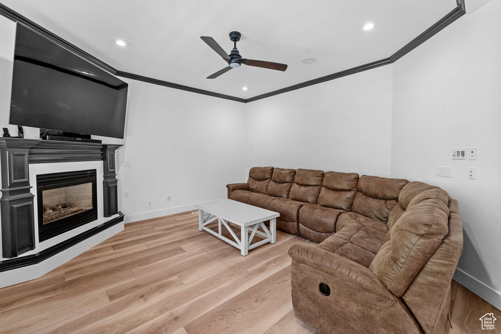 Living room featuring light hardwood / wood-style floors, crown molding, and ceiling fan