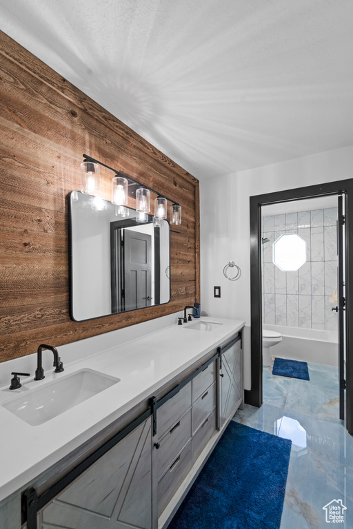 Bathroom with tile floors, toilet, wooden walls, and double sink vanity