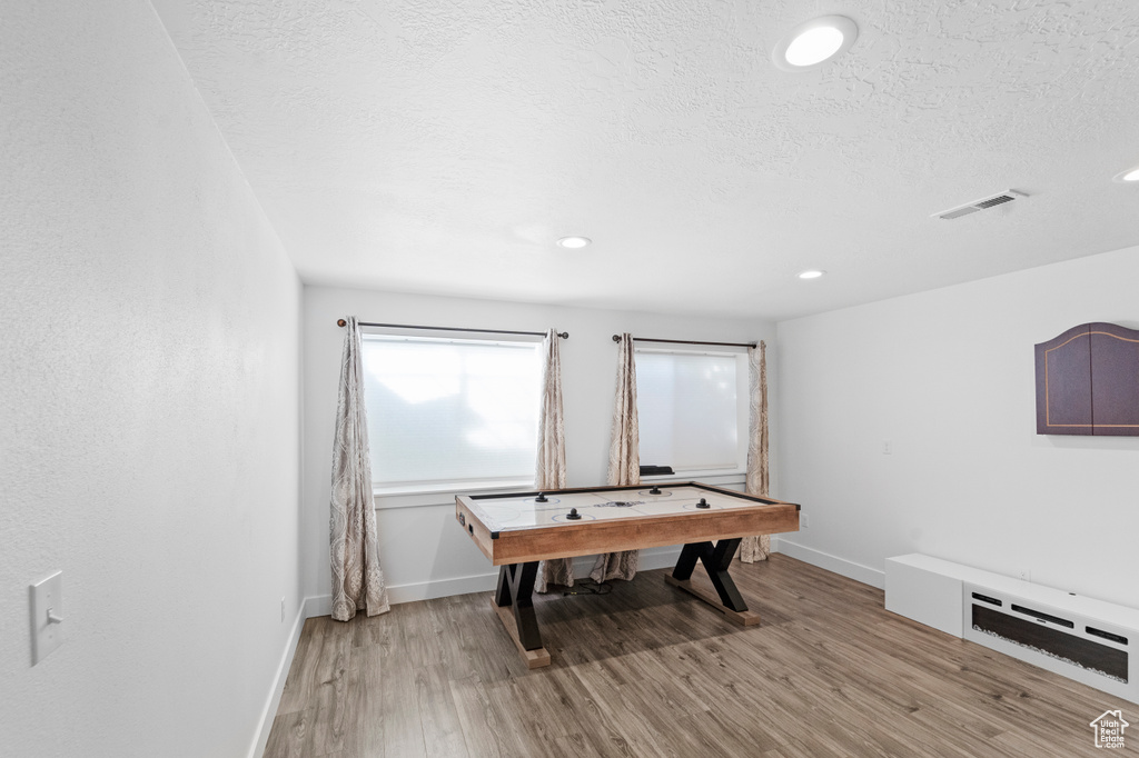 Recreation room with a textured ceiling and hardwood / wood-style flooring