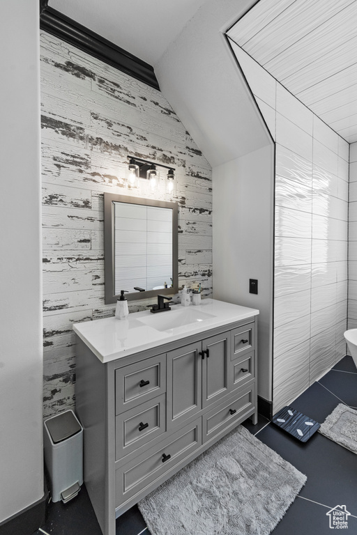 Bathroom with tile walls, vaulted ceiling, vanity, and tile flooring