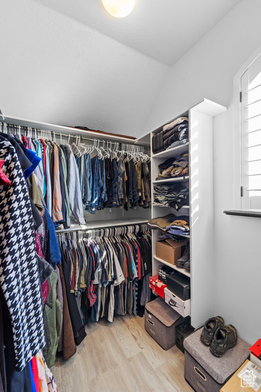 Spacious closet featuring hardwood / wood-style floors and vaulted ceiling