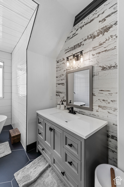 Bathroom with tile floors, tile walls, large vanity, a bathing tub, and vaulted ceiling
