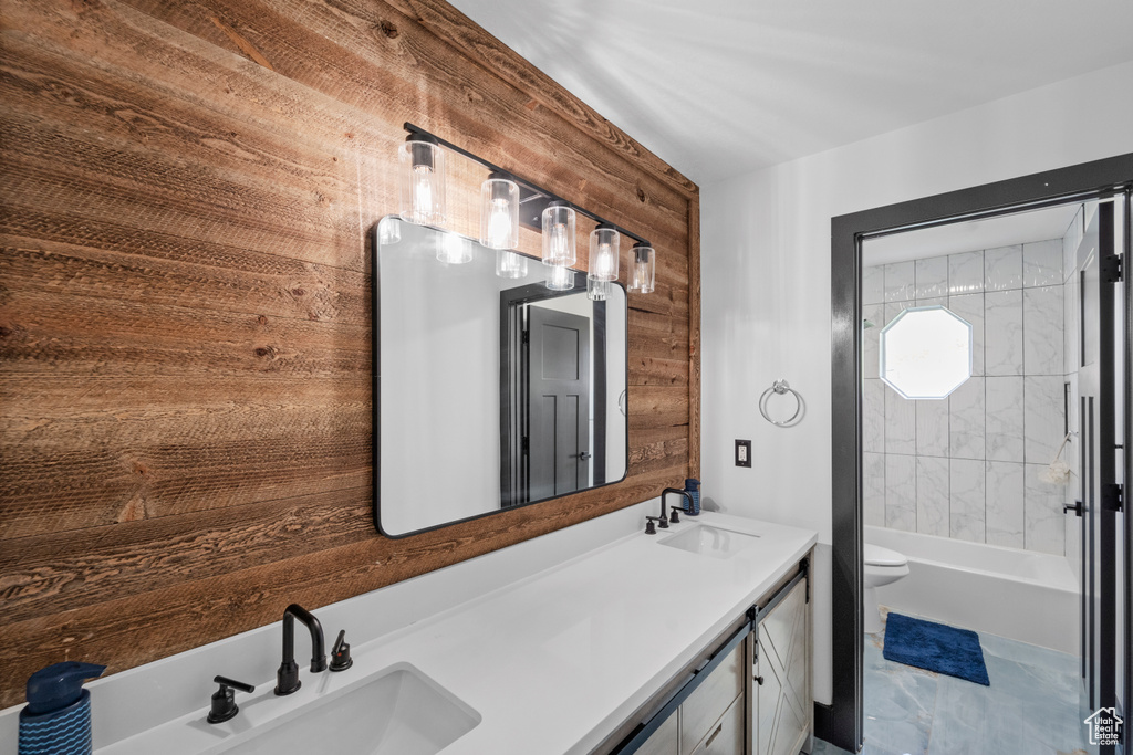 Bathroom featuring wood walls, tile floors, toilet, and dual vanity