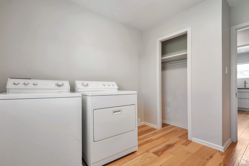 Washroom with independent washer and dryer and light hardwood / wood-style floors