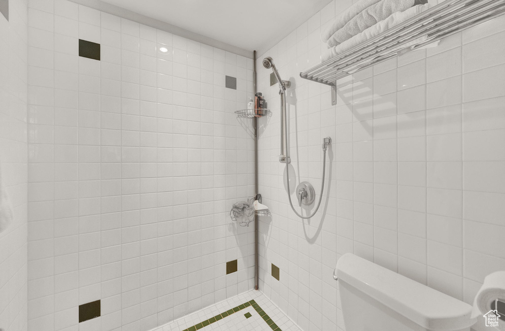 Bathroom featuring toilet, tile walls, and a tile shower
