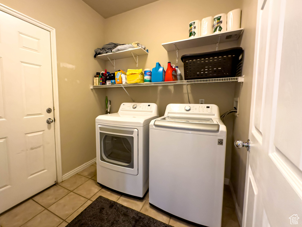 Clothes washing area featuring washing machine and dryer and light tile floors