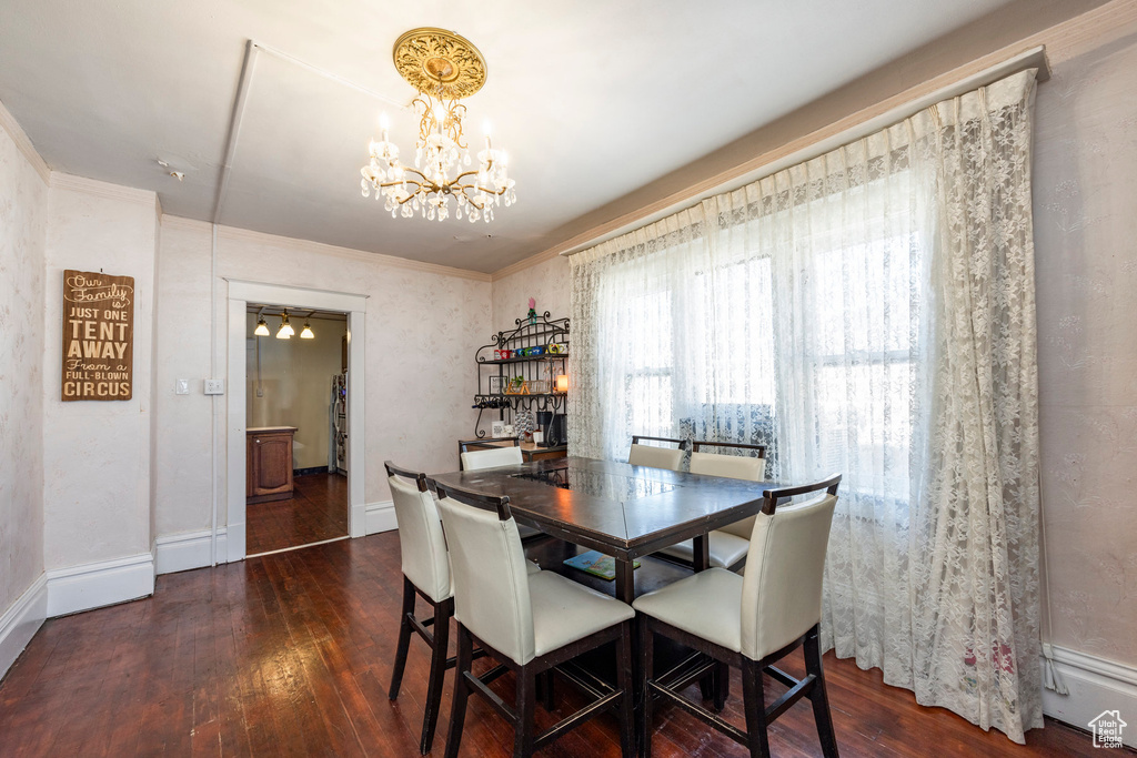 Dining area with ornamental molding, dark hardwood / wood-style flooring, and a notable chandelier
