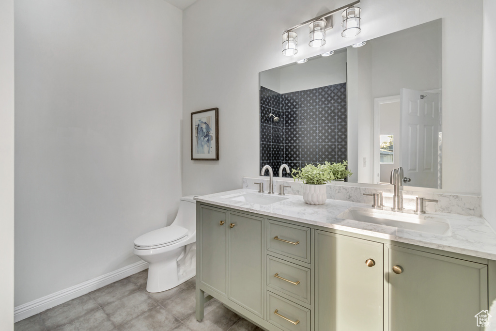 Bathroom featuring dual bowl vanity, toilet, and tile flooring