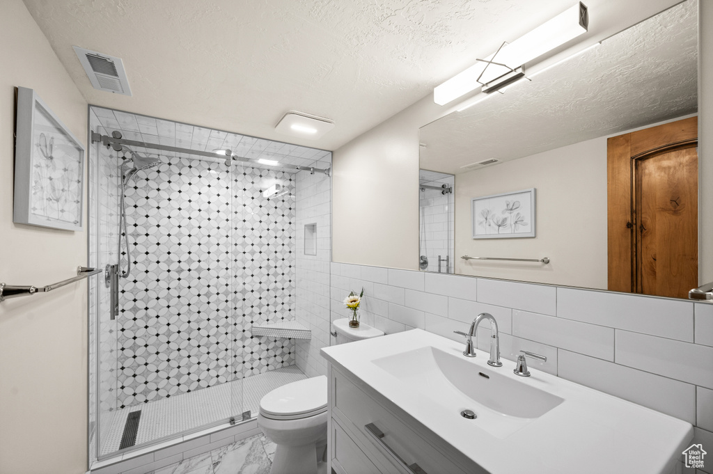 Bathroom featuring tile walls, tasteful backsplash, tile floors, toilet, and vanity