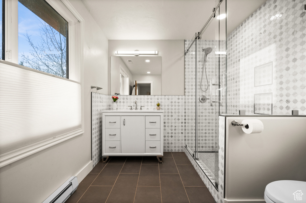 Bathroom with backsplash, a shower with shower door, toilet, vanity with extensive cabinet space, and tile flooring
