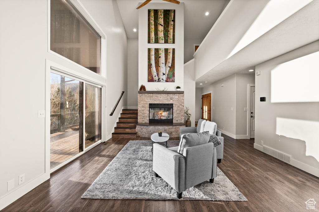 Living room featuring a fireplace, a towering ceiling, and dark wood-type flooring