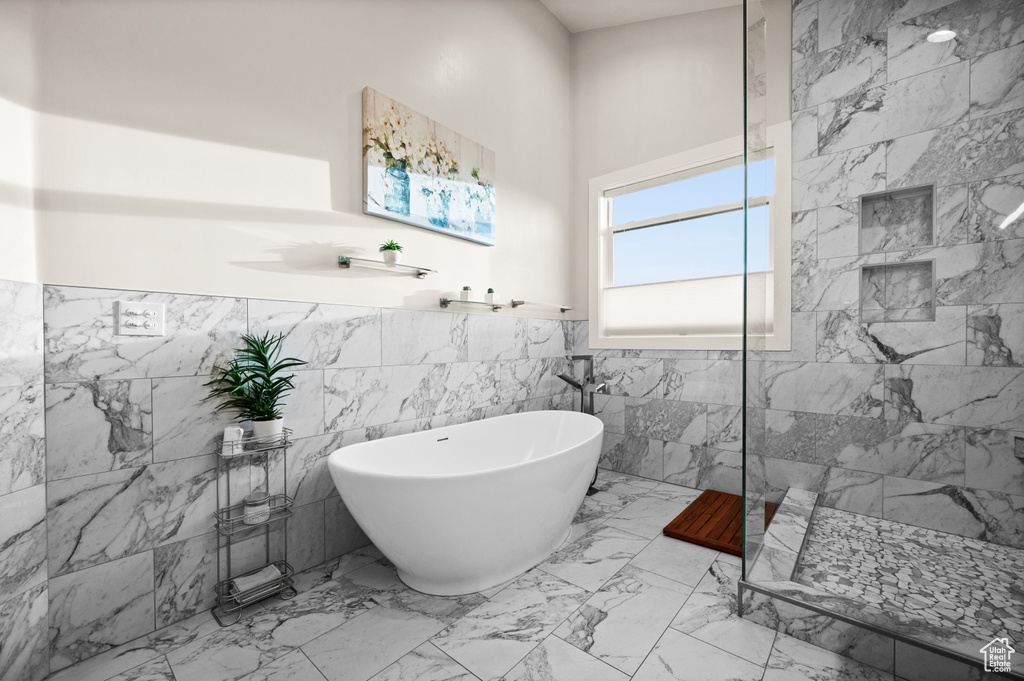 Bathroom featuring tile walls, shower with separate bathtub, and tile floors