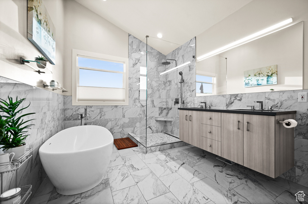 Bathroom featuring oversized vanity, tile walls, shower with separate bathtub, and tile floors