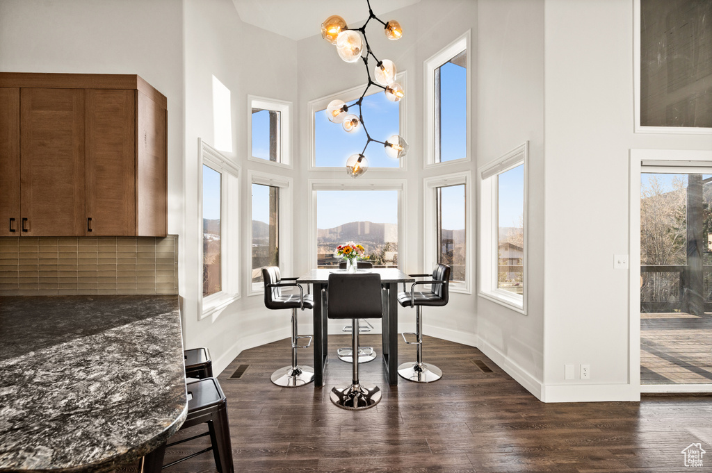 Dining area with an inviting chandelier, a mountain view, a towering ceiling, and dark wood-type flooring