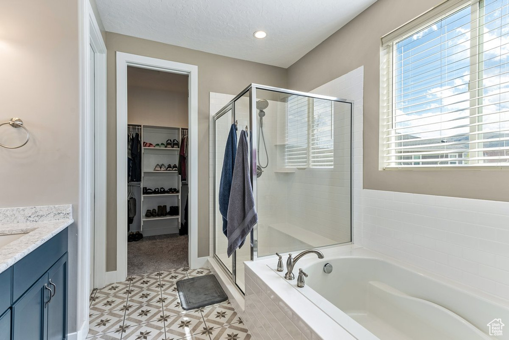 Bathroom with independent shower and bath, a healthy amount of sunlight, and tile floors