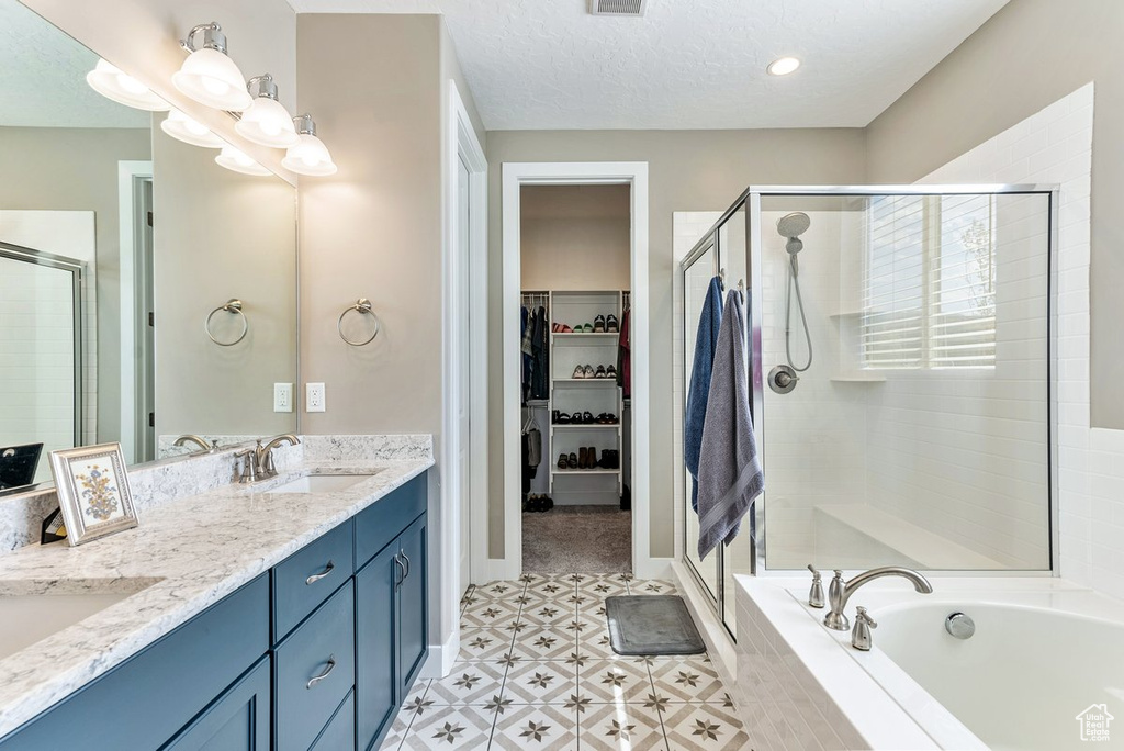 Bathroom with tile flooring, separate shower and tub, large vanity, a textured ceiling, and dual sinks