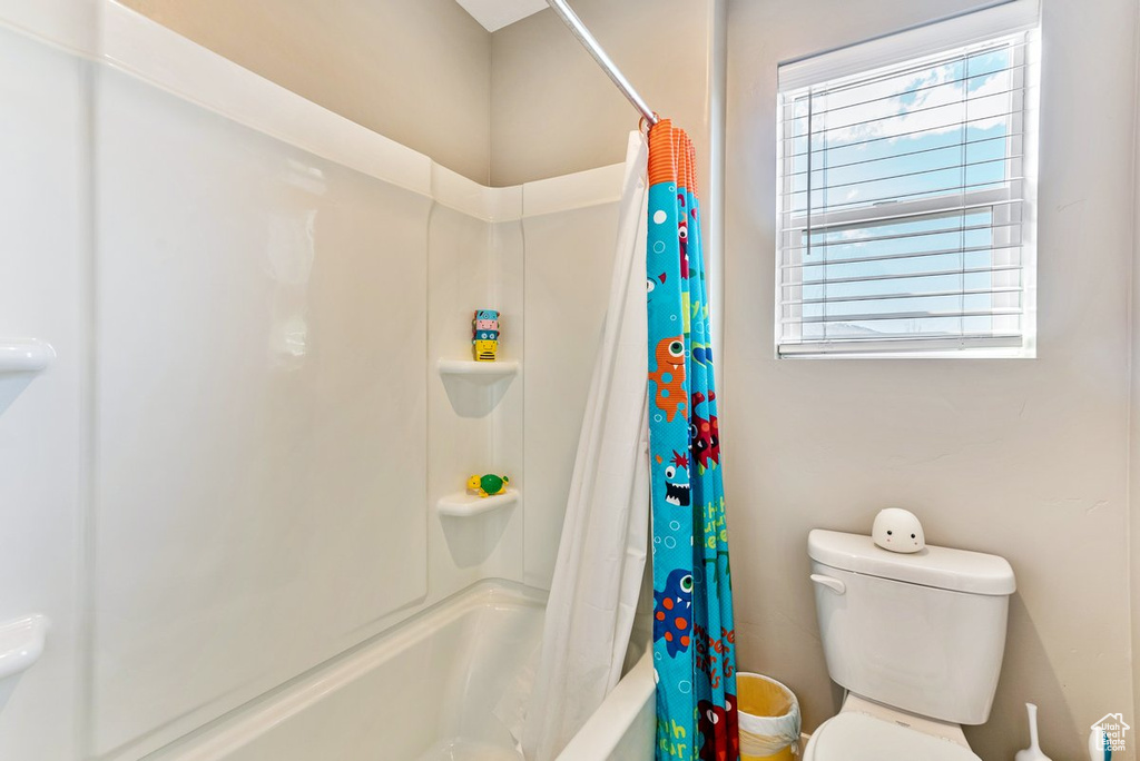 Bathroom with shower / bathtub combination with curtain and toilet
