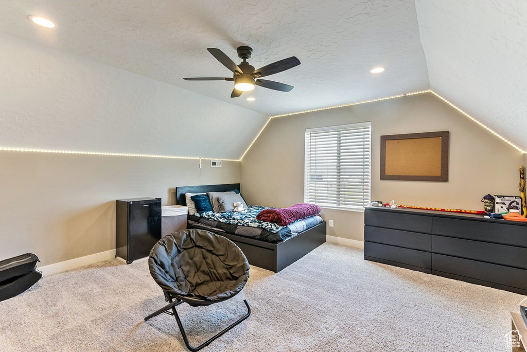 Carpeted bedroom featuring ceiling fan, a textured ceiling, and lofted ceiling