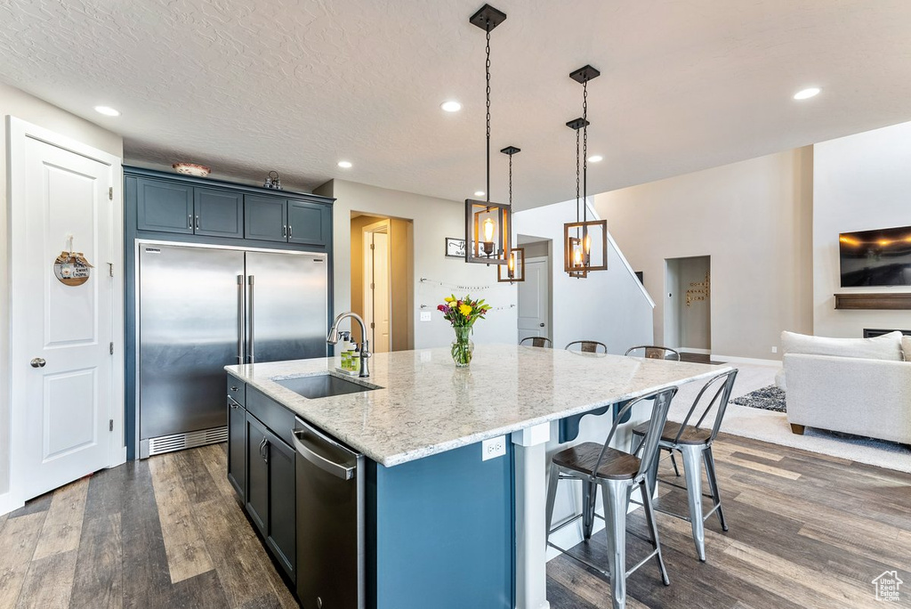 Kitchen featuring sink, appliances with stainless steel finishes, a kitchen island with sink, and dark hardwood / wood-style floors