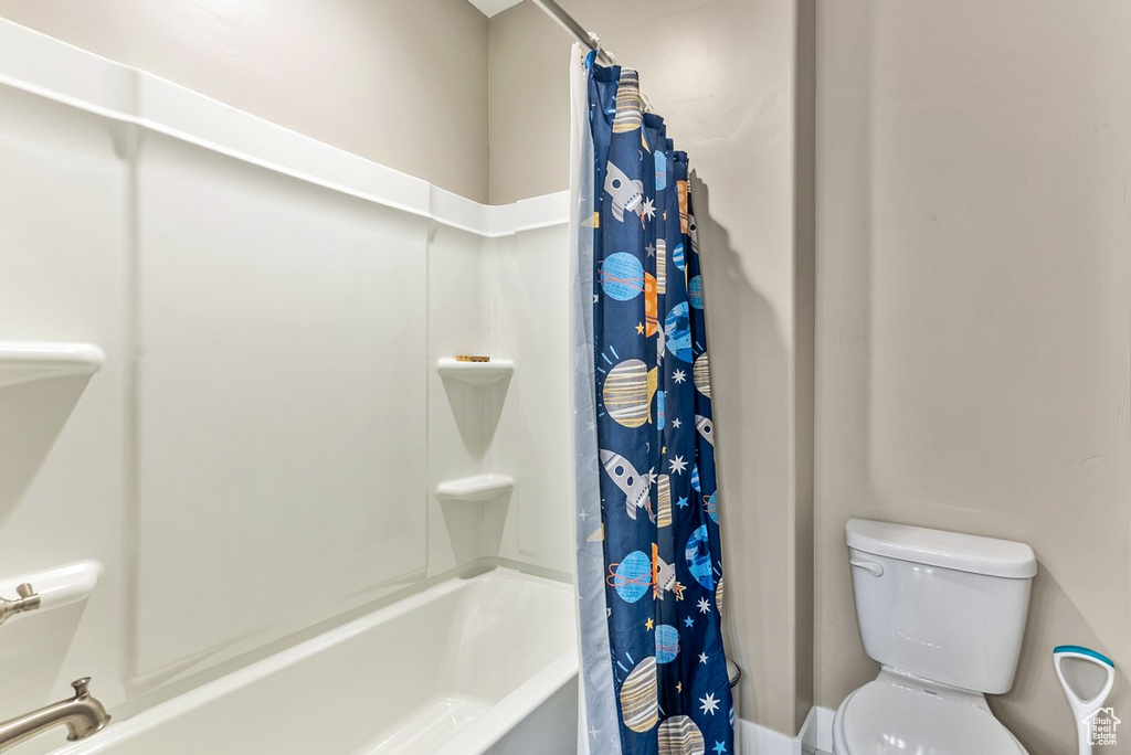 Bathroom with toilet and shower / bath combination with curtain
