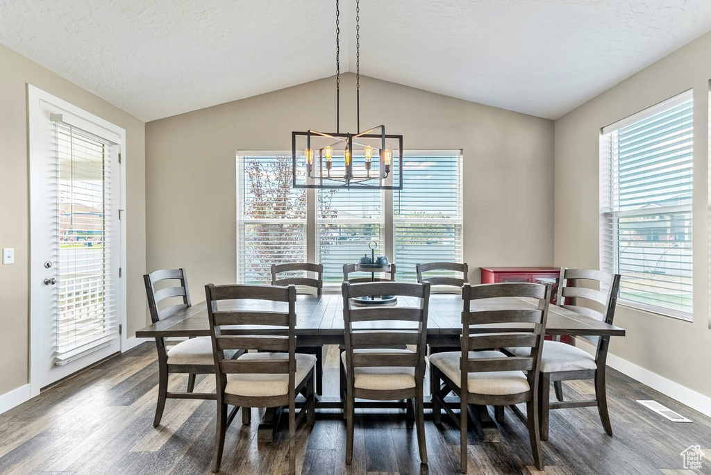 Dining area featuring plenty of natural light, dark hardwood / wood-style floors, and vaulted ceiling