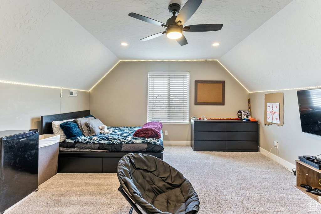 Carpeted bedroom featuring refrigerator, ceiling fan, a textured ceiling, and lofted ceiling
