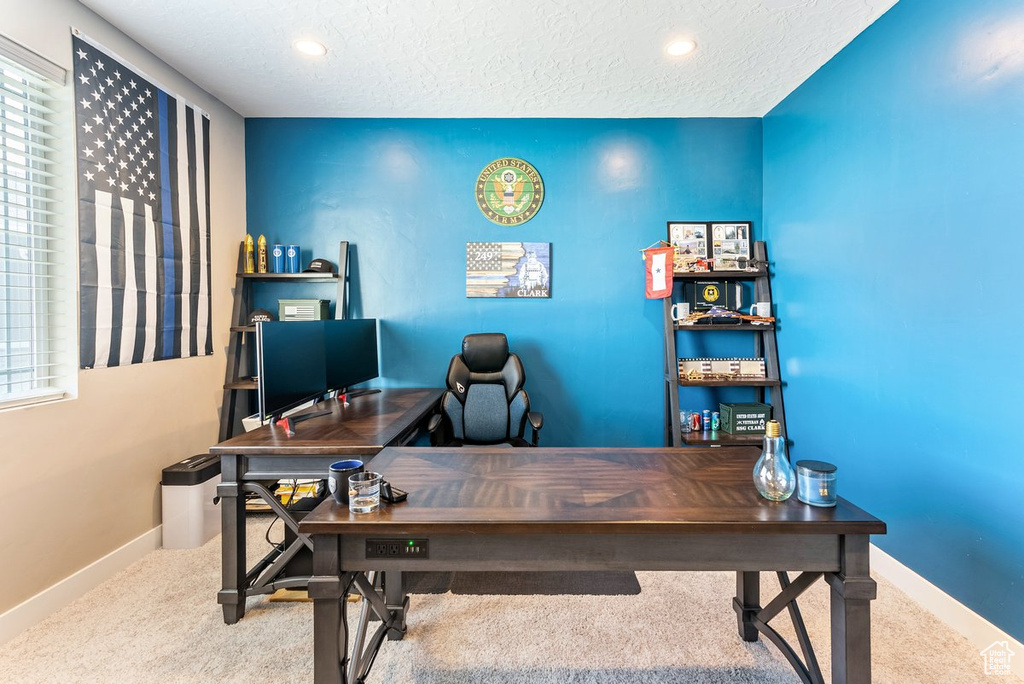 Carpeted home office featuring a textured ceiling