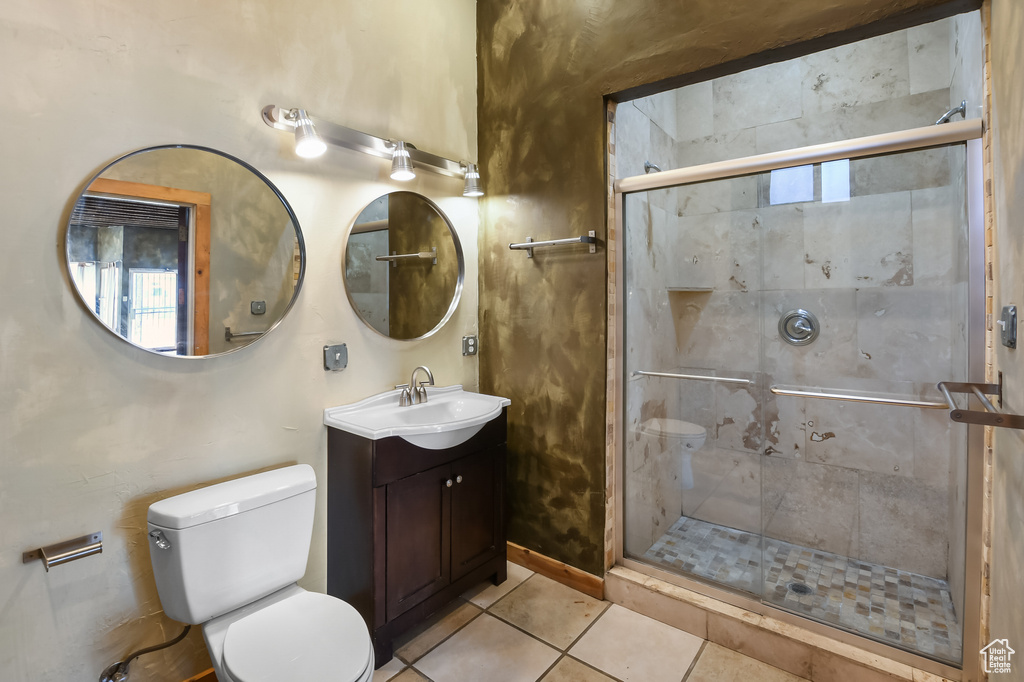 Bathroom with walk in shower, tile floors, vanity with extensive cabinet space, and toilet