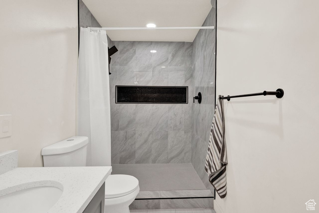 Bathroom featuring walk in shower, vanity, and toilet