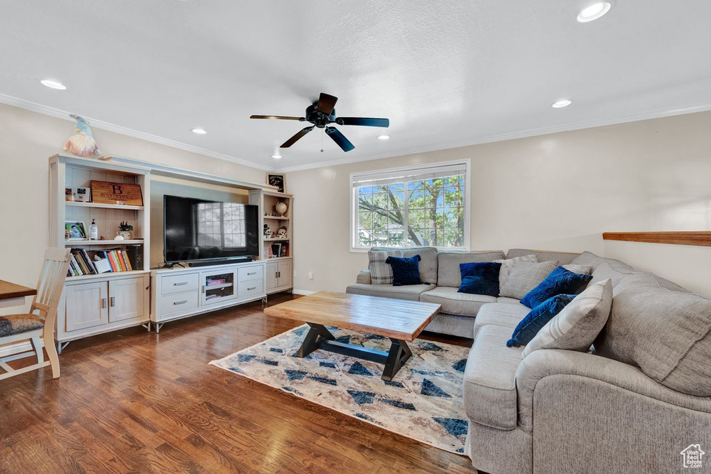 Living room with ornamental molding, dark wood-type flooring, and ceiling fan