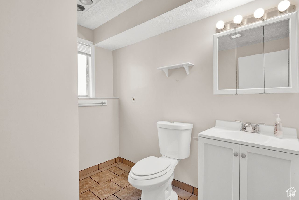 Bathroom featuring a textured ceiling, vanity, tile floors, and toilet