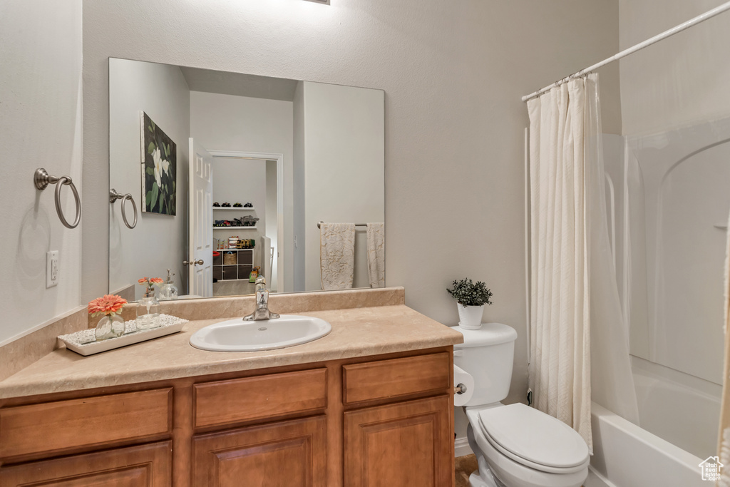 Full bathroom with toilet, large vanity, and shower / tub combo with curtain