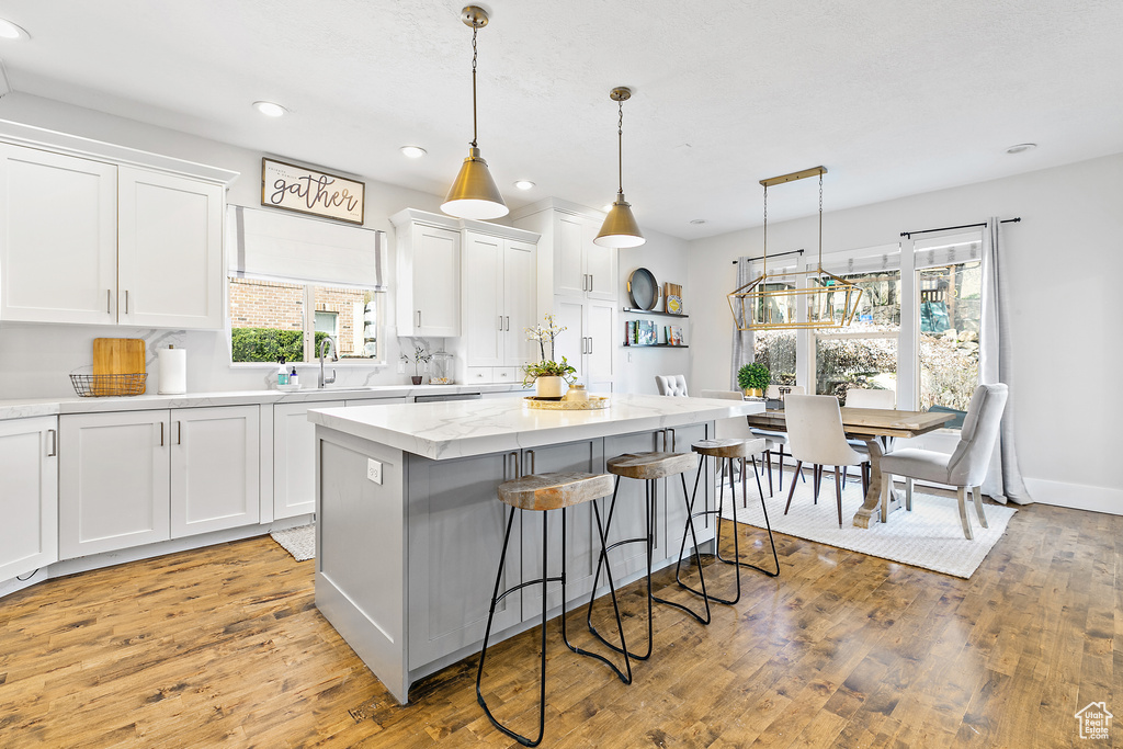 Kitchen featuring pendant lighting, light wood-type flooring, and white cabinetry