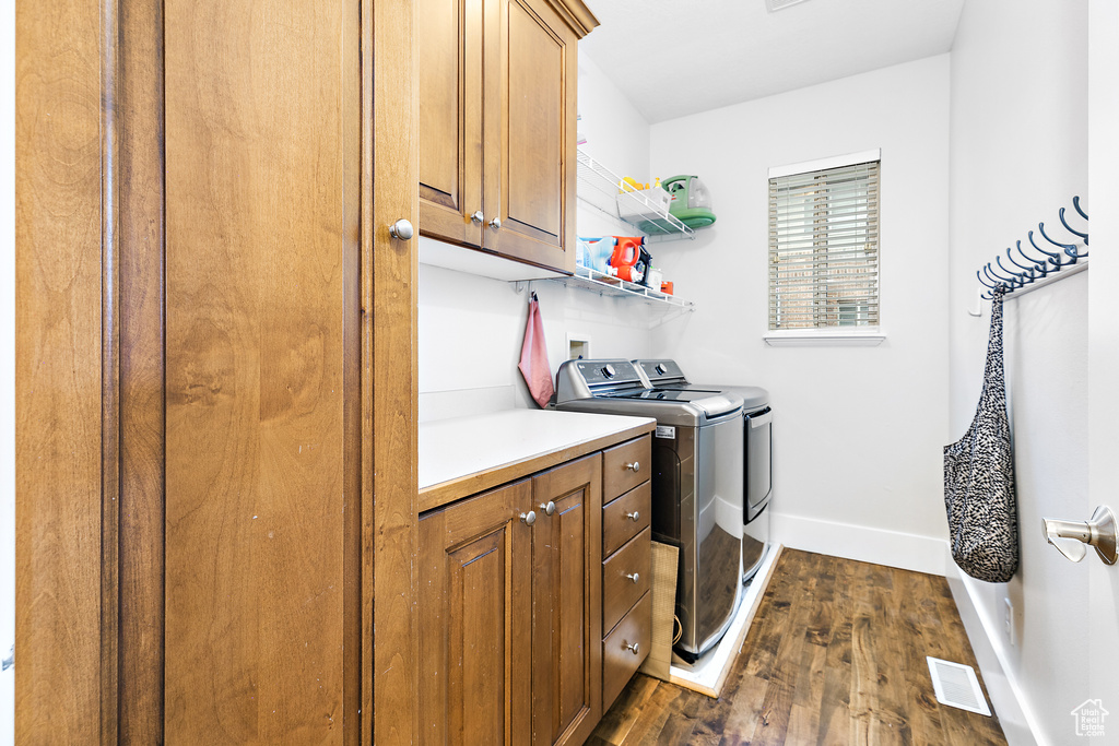 Laundry room with cabinets, washer and clothes dryer, dark wood-type flooring, and hookup for a washing machine